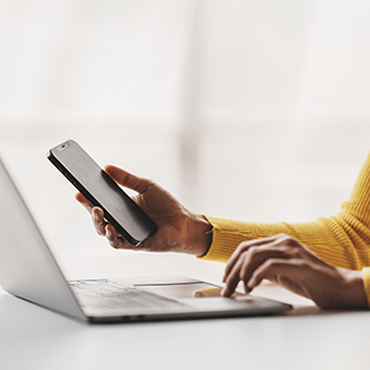 A person with a laptop, holding a mobile phone