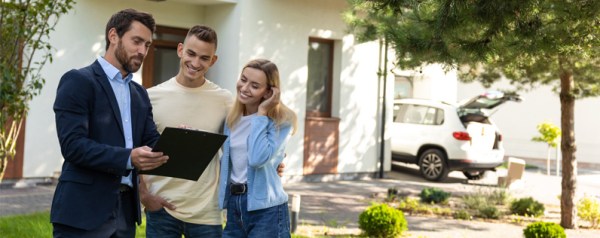 A real estate agent showing a couple property information on a tablet