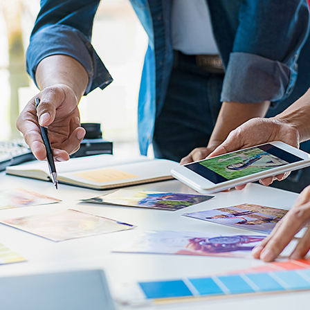 Two pairs of hands hover over a table filled with color swatches and photographs.