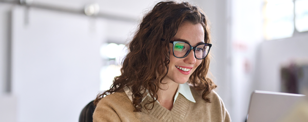 A woman smiling in front of her laptop.