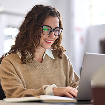 A woman smiling in front of her laptop.