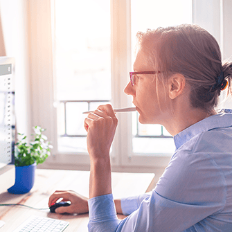 A woman looks into a computer monitor displaying an email inbox.