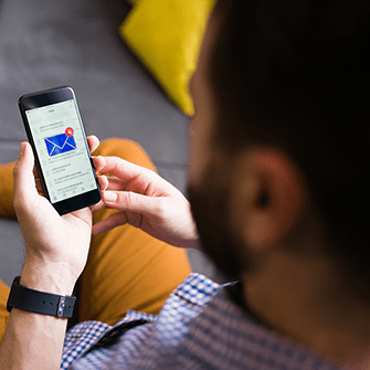 A man holds a smartphone displaying his email inbox.