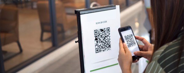 A woman scans a QR code outside of a business