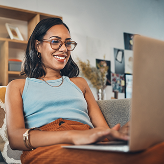 A woman smiling as she looks at her laptop