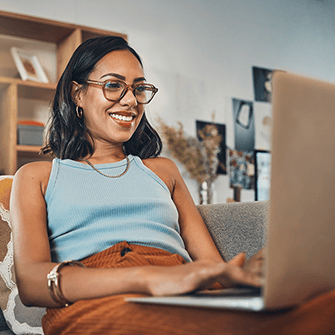A woman smiling as she looks at her laptop
