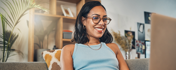 A woman smiling as she looks at her laptop