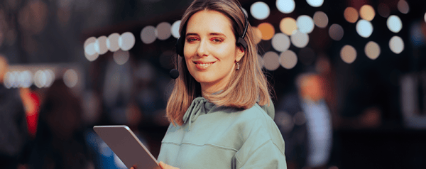 A woman wearing a headset holds a clipboard.